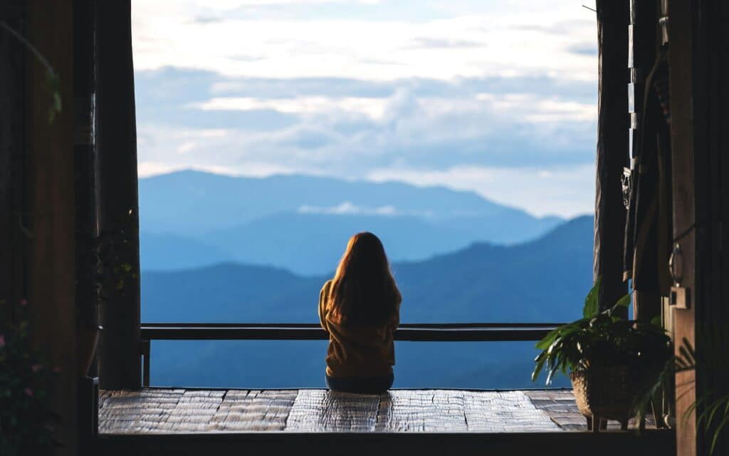 a female traveler sitting and looking at a beautiful mountain and nature view before sunset