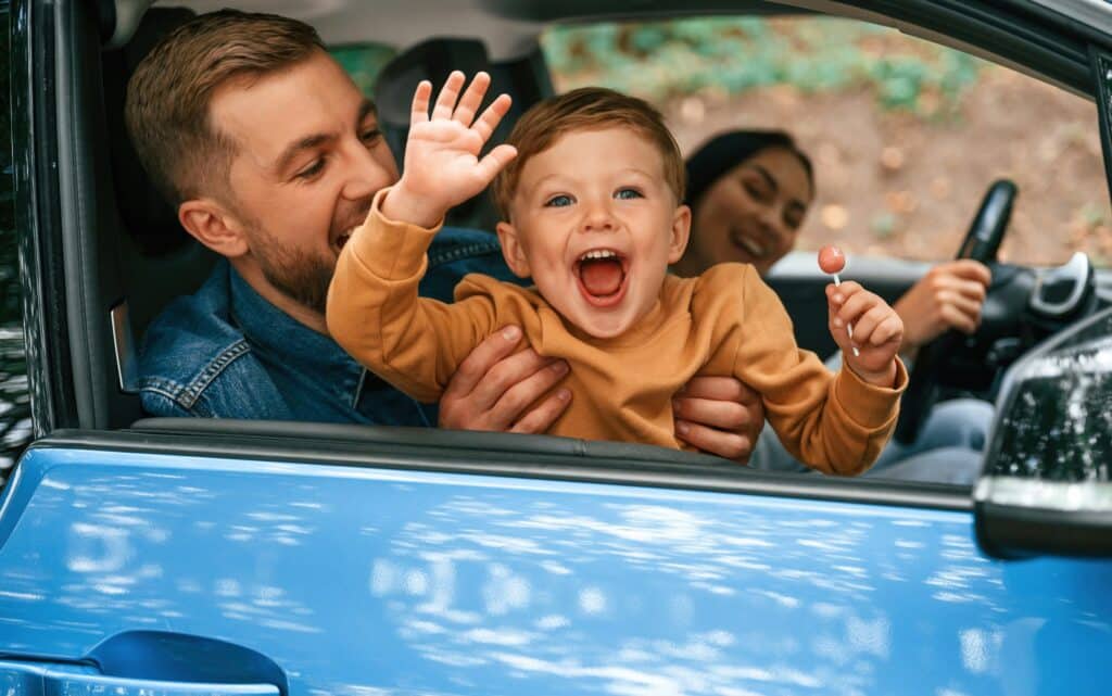 Family of father, mother and little son are sitting in the modern car